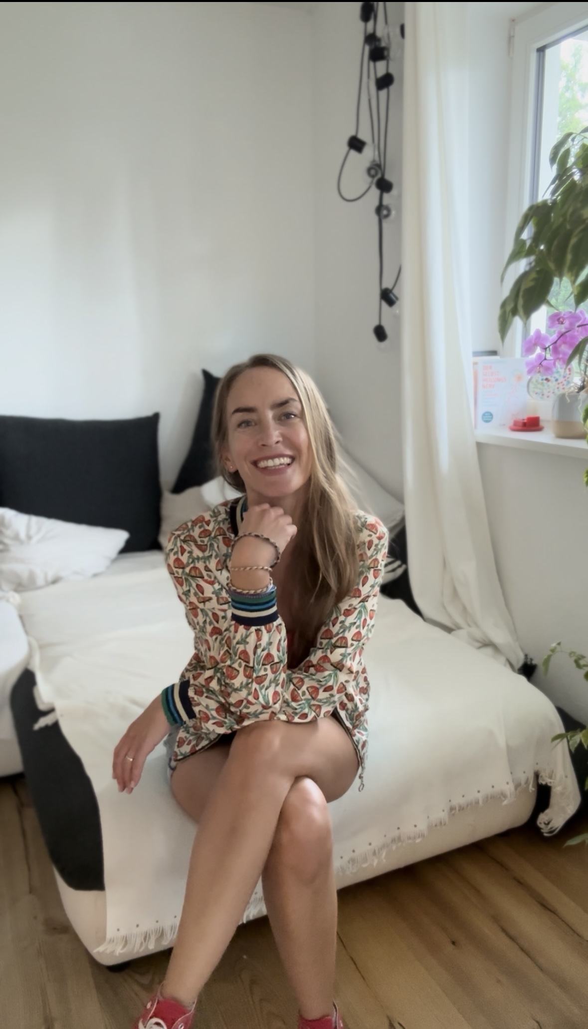 Anna Schmid sitzt lachend auf einer Tagesdecke in ihrem Praxisraum.